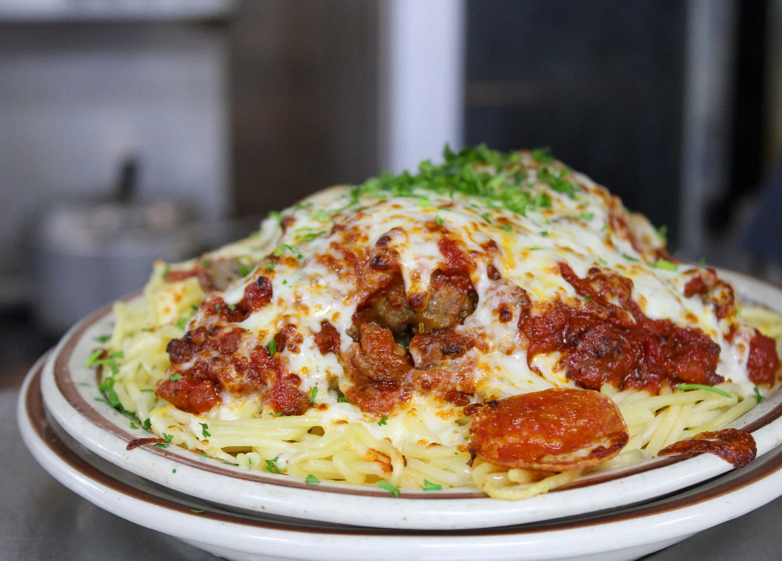 Baked meatlovers spaghetti — meatballs, sausage, marinara, and melted mozzarella over spaghetti